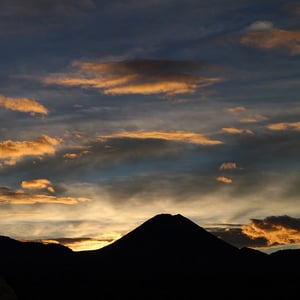 Dark silhouette of Mt Ngauruhoe with wispy dark and bright clouds at sunrise