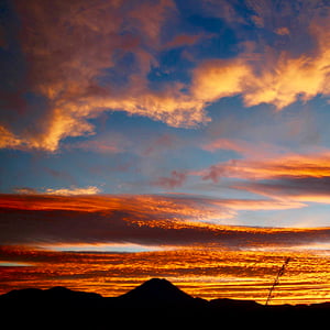 Dark silhouette of Mt Ngauruhoe with stripes of bright red and orange sky at sunrise 