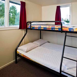 Queen bed and single bunk bed on top inside camping hut at Discovery Lodge Tongariro National Park