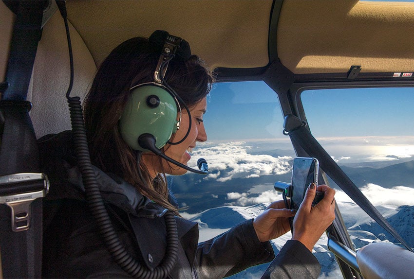 Happy passenger taking helicopter flight with Tongariro National Park our the window