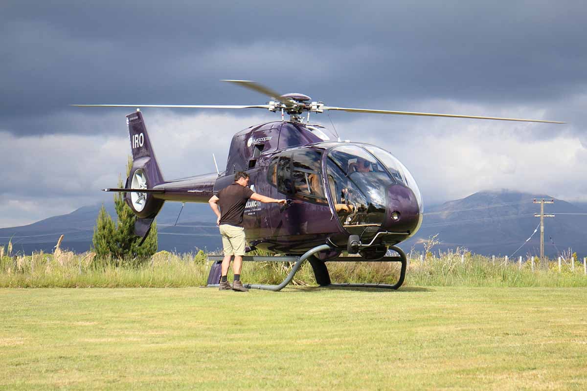 Volcanic Air ZK-IRO and pilot at Discovery helipad on a dark sky day
