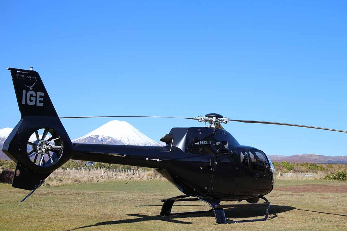 Helicorp ZK-IGE with snow-capped Mt Ngauruhoe in the background parked at Discovery helipad