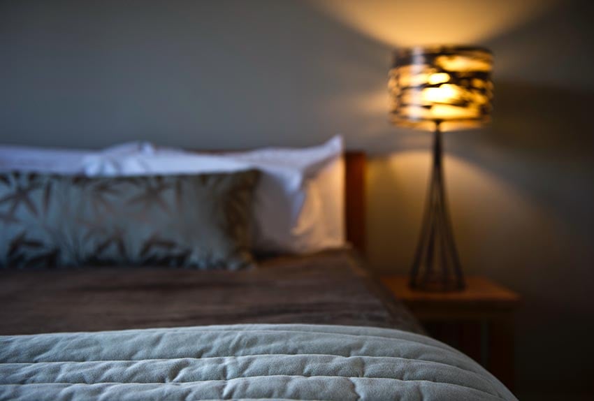 Luxury bed and hand made lamp inside a Discovery Lodge chalet at Tongariro National Park