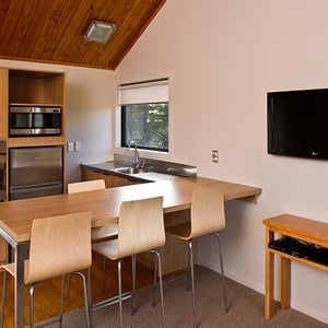 Kitchen with microwave, fridge dinning bar and TV in a one bedroom chalet at Discovery Lodge Tongariro National Park