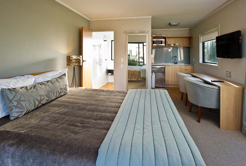 Superior queen bed, Kitchen, private bathroom, TV, desk inside chalet studio at Discovery Lodge Tongariro National Park