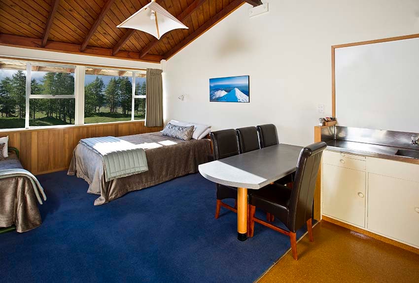 Kitchen, dinning table, queen bed, single bed and views over alpine meadows from motel studio at Discovery Lodge Tongariro