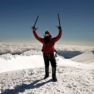 Man at top of mountain surrounded by snow