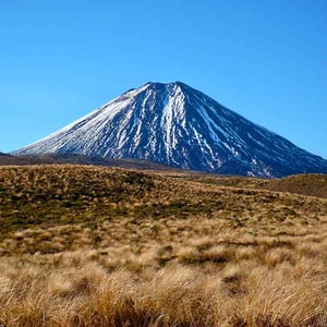 The active volcano of Mt Ngauruhoe with blue sky and golden tussock grass 