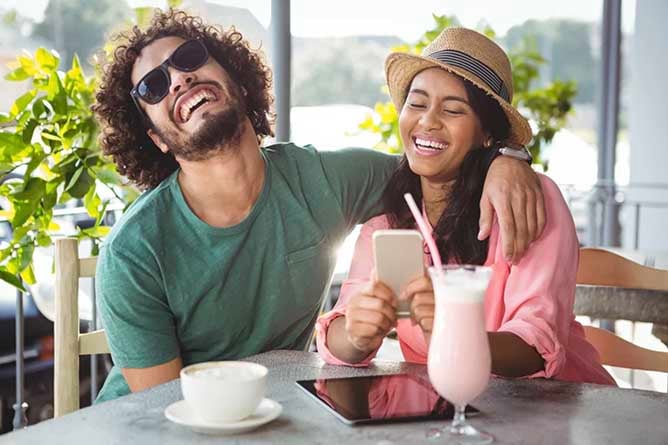 A couple laughing and enjoying a coffee and smoothy at a cafe close to Discovery Lodge Tongariro