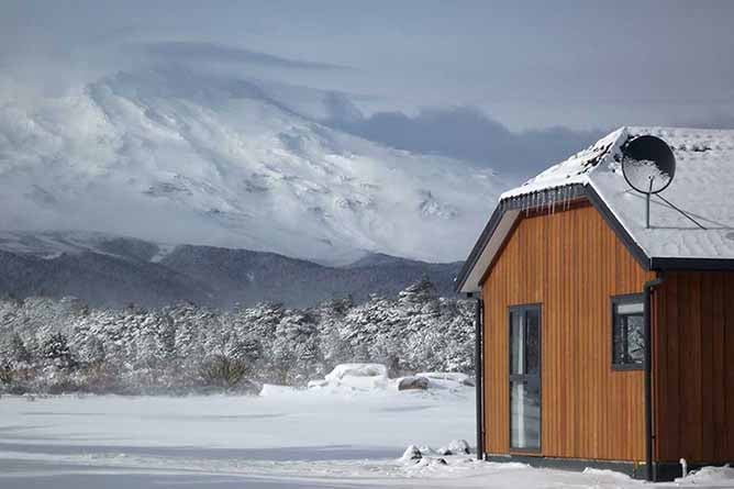 A Discovery Lodge chalet surrounded by snow with Whakapapa Mt Ruapehu in the background