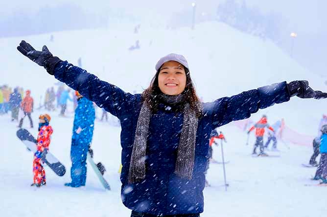 A young lady having fun in the snow with snow boarders and skiers in the background