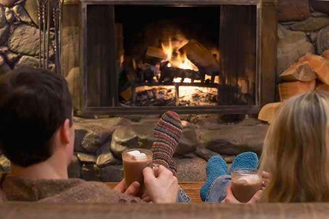 A couple enjoying hot chocolates at a cafe bar next to an open fire